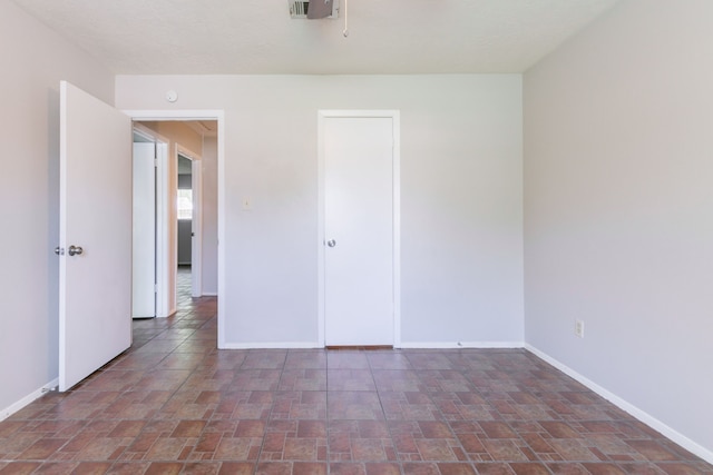 empty room featuring stone finish flooring, baseboards, and visible vents