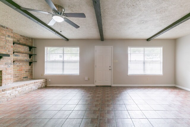 unfurnished living room featuring baseboards, a textured ceiling, and beamed ceiling