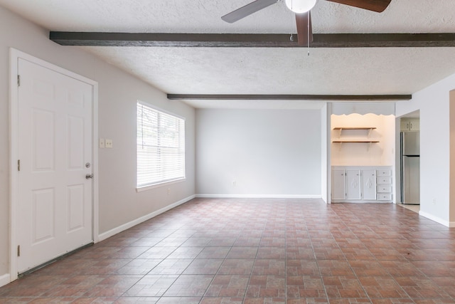 unfurnished living room with beamed ceiling, a textured ceiling, a ceiling fan, and baseboards