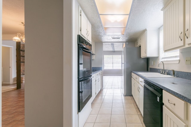 kitchen featuring black appliances, white cabinetry, a sink, and light tile patterned floors