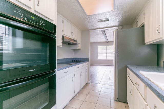 kitchen with a textured ceiling, white cabinetry, black appliances, under cabinet range hood, and light tile patterned floors