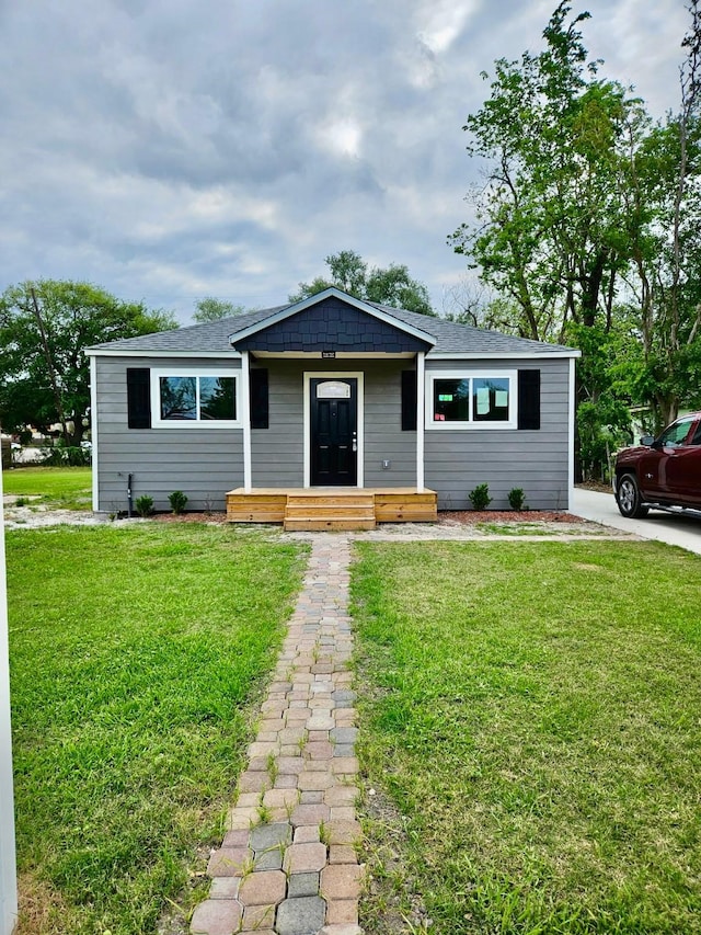 view of front of property featuring a shingled roof and a front lawn