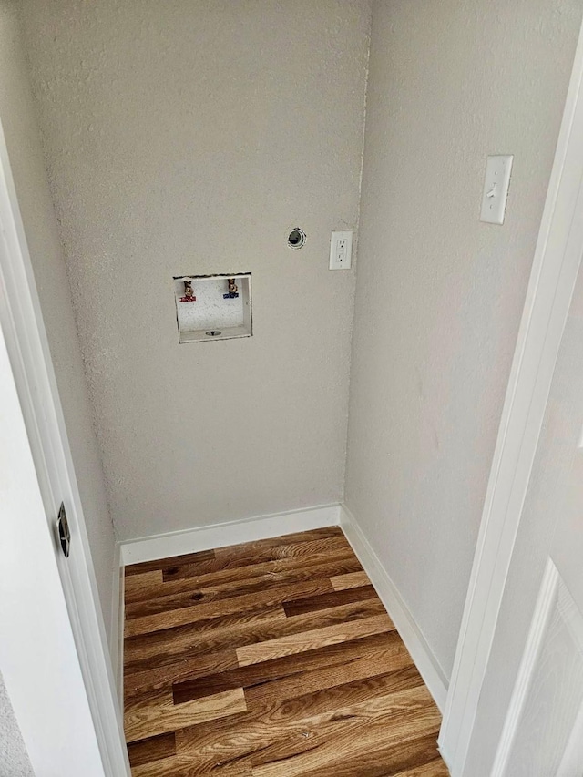 washroom with washer hookup, wood finished floors, and baseboards