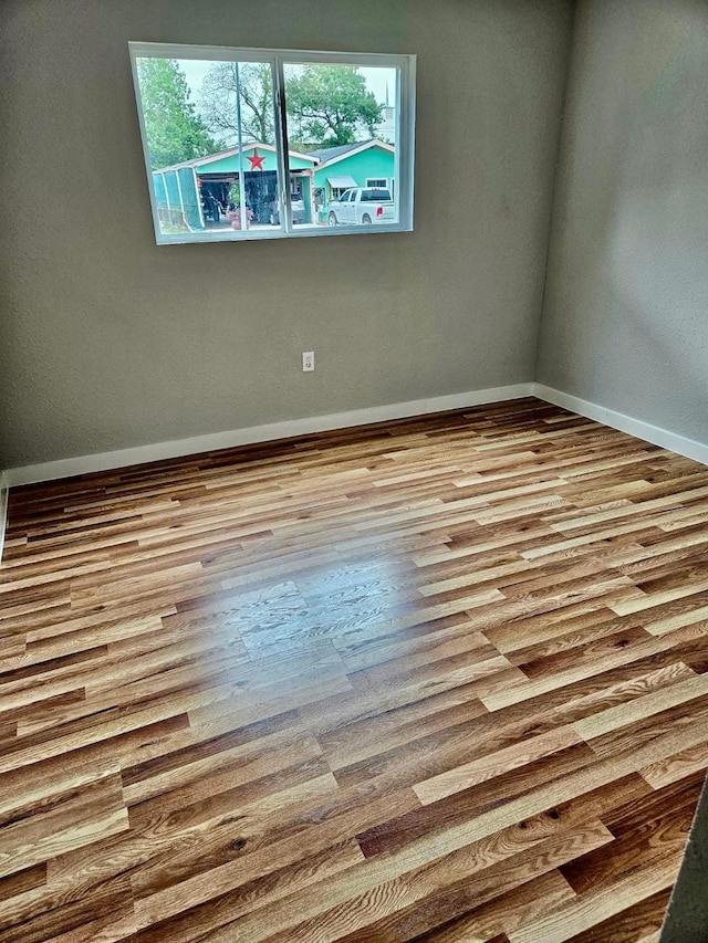 empty room with baseboards and wood finished floors