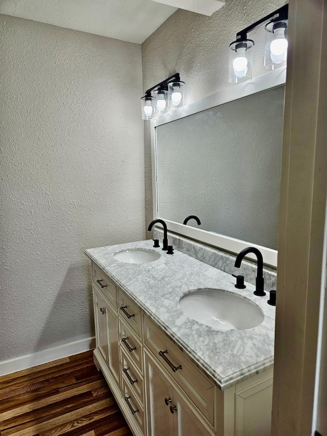 full bath with a textured wall, wood finished floors, and a sink