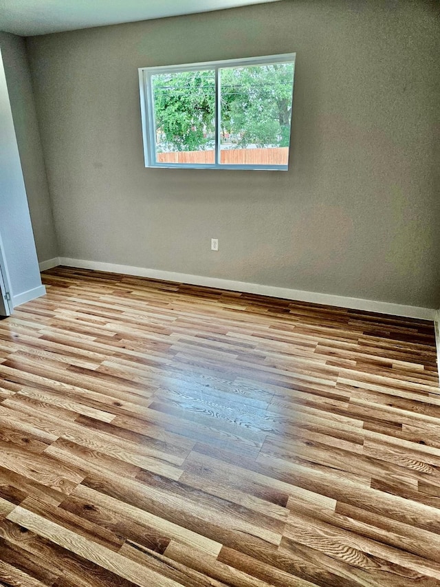 spare room featuring baseboards and wood finished floors