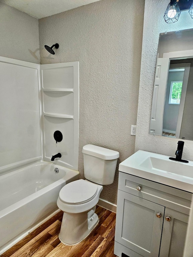 full bath with toilet, shower / washtub combination, wood finished floors, a textured wall, and vanity