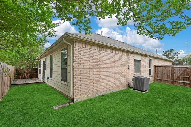 rear view of property with cooling unit, a lawn, a wooden deck, and a fenced backyard