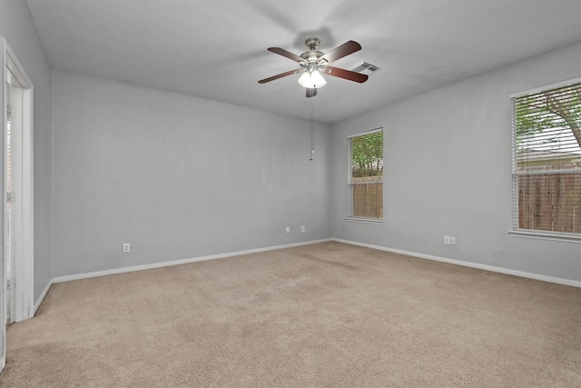 empty room featuring light carpet, a ceiling fan, visible vents, and a healthy amount of sunlight