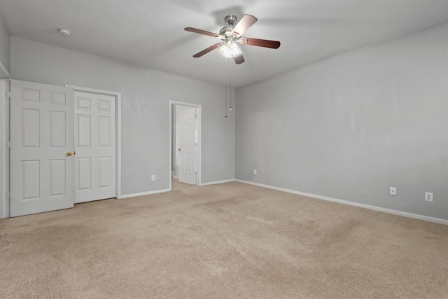 unfurnished bedroom featuring light carpet, a ceiling fan, and baseboards