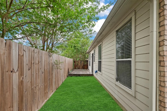 view of property exterior featuring fence, a yard, and a deck
