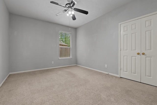 unfurnished bedroom featuring baseboards, carpet floors, a closet, and ceiling fan