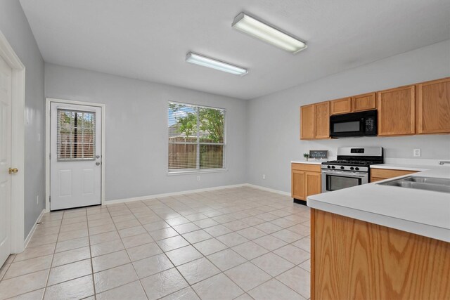 kitchen with a sink, black microwave, a wealth of natural light, light countertops, and stainless steel range with gas stovetop