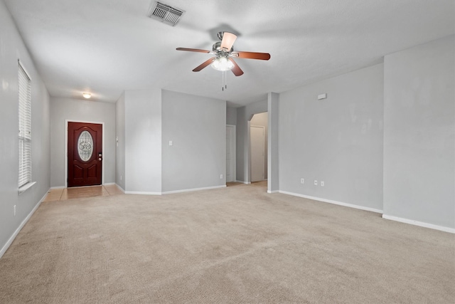 unfurnished living room with light colored carpet, baseboards, a ceiling fan, and visible vents