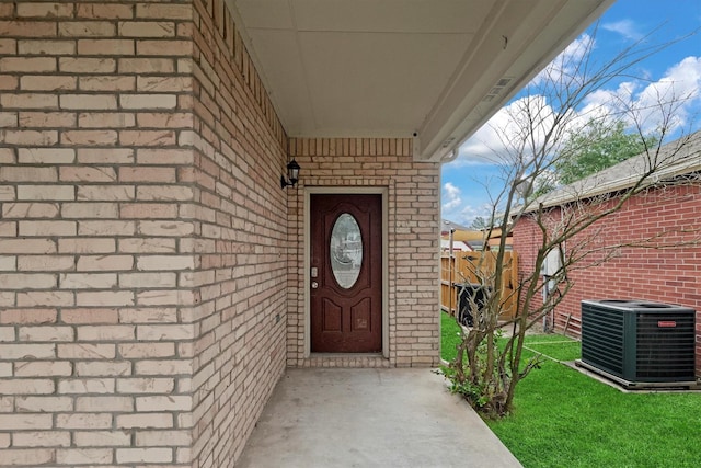 entrance to property featuring fence, brick siding, and central AC