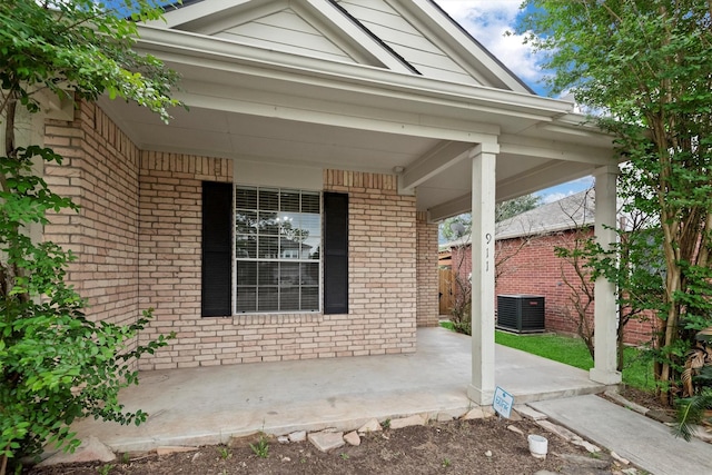 property entrance featuring central air condition unit, brick siding, and covered porch