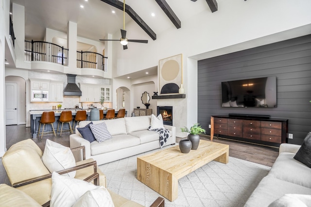 living room featuring a ceiling fan, arched walkways, wood finished floors, and a high end fireplace