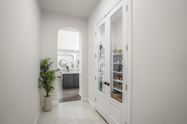corridor featuring baseboards and arched walkways