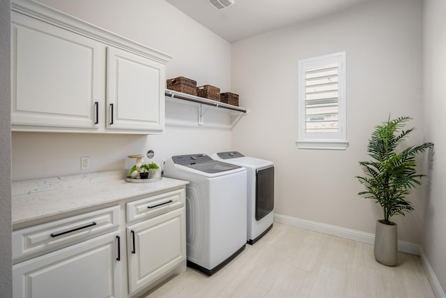 washroom with cabinet space, baseboards, visible vents, and washing machine and dryer