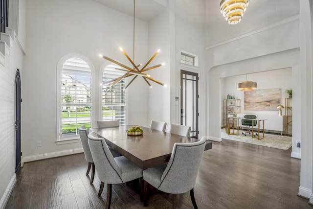 dining room with baseboards, dark wood-style floors, a chandelier, and a towering ceiling