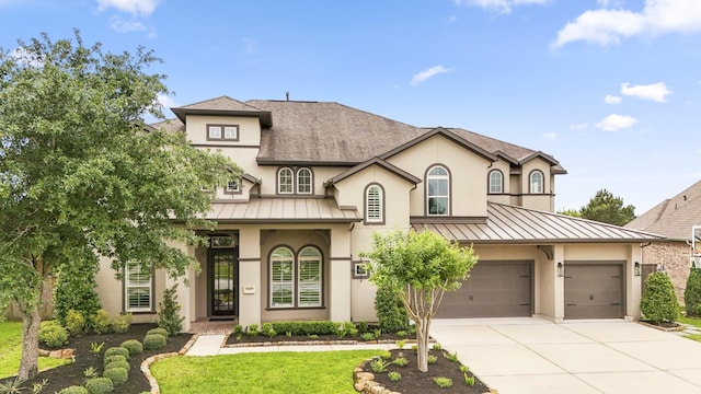 french country inspired facade featuring concrete driveway, a standing seam roof, metal roof, and stucco siding