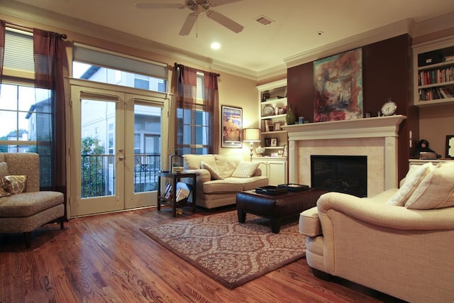 living room with a ceiling fan, wood finished floors, french doors, ornamental molding, and visible vents