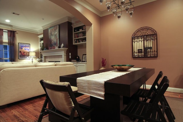 dining area featuring a notable chandelier, crown molding, wood finished floors, and visible vents