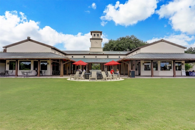 rear view of property with a patio area, a yard, and metal roof