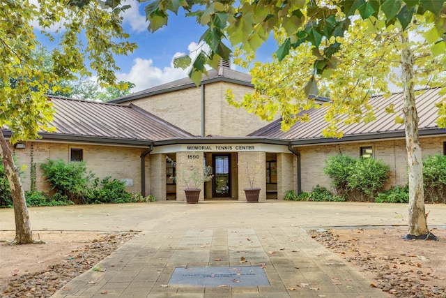 view of front of property featuring brick siding and metal roof