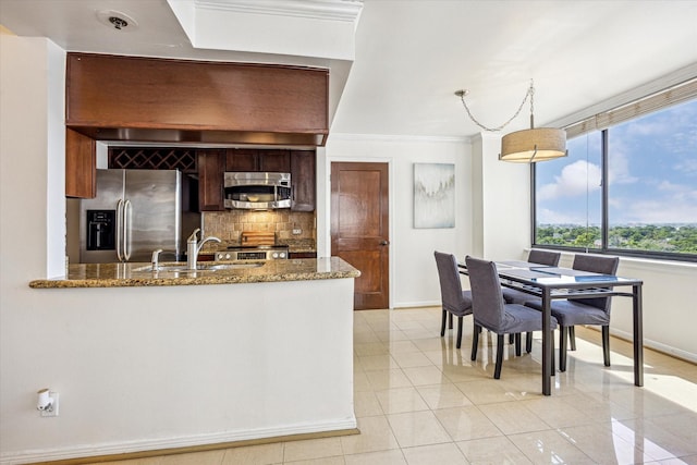 kitchen with a sink, light tile patterned floors, stone countertops, stainless steel appliances, and baseboards