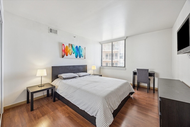 bedroom with wood finished floors, visible vents, and baseboards
