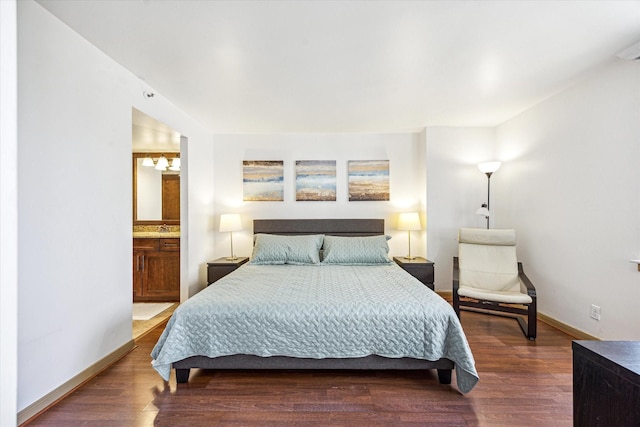bedroom featuring baseboards, ensuite bathroom, wood finished floors, and a sink