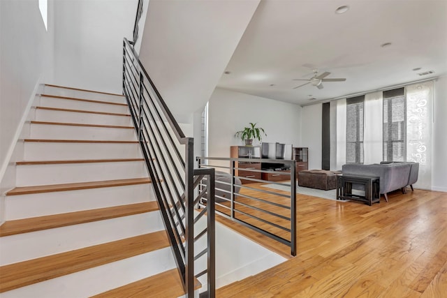 stairway with a ceiling fan, visible vents, and wood finished floors