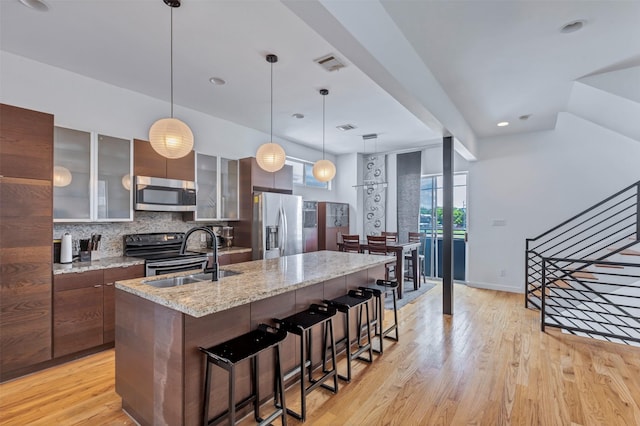 kitchen with a sink, appliances with stainless steel finishes, light wood finished floors, and visible vents