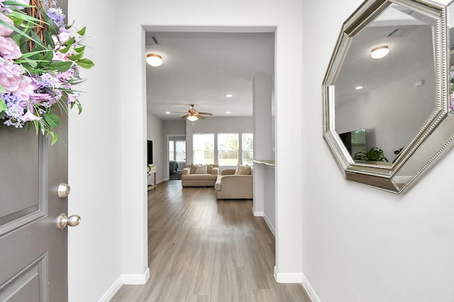 corridor with baseboards, recessed lighting, and light wood-style flooring