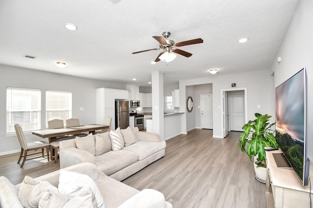 living room with visible vents, baseboards, recessed lighting, light wood-type flooring, and a ceiling fan