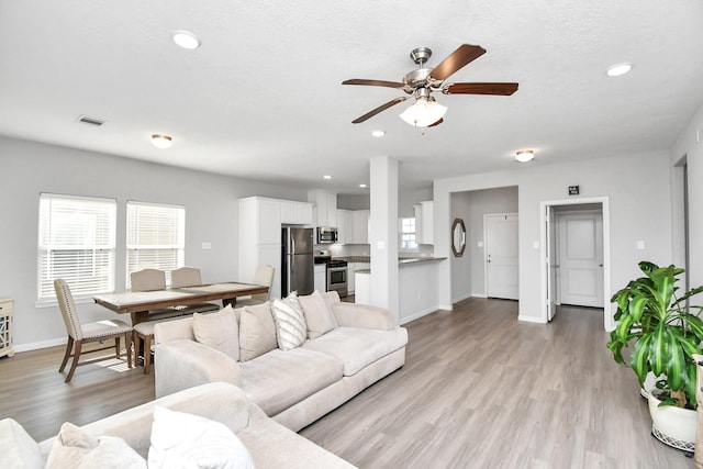 living area with visible vents, baseboards, ceiling fan, recessed lighting, and light wood finished floors