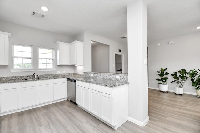kitchen featuring white cabinets, a sink, light wood finished floors, stainless steel dishwasher, and visible vents