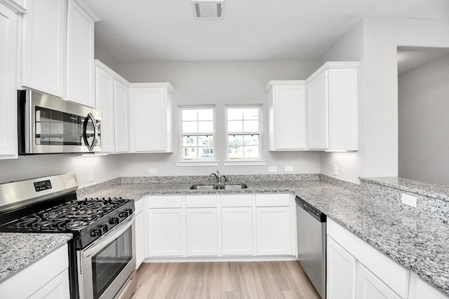 kitchen featuring appliances with stainless steel finishes, a sink, visible vents, and light wood-type flooring
