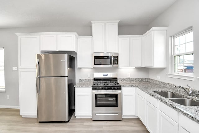 kitchen featuring a sink, light wood-style flooring, white cabinetry, and stainless steel appliances