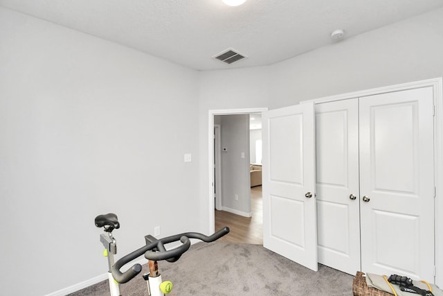 exercise room with visible vents, baseboards, and carpet floors