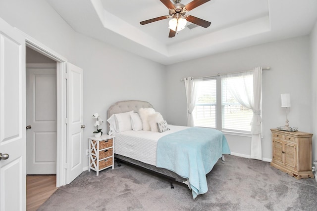 bedroom featuring a raised ceiling, baseboards, and ceiling fan