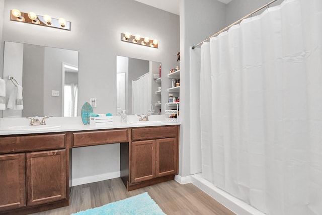 bathroom with a shower with shower curtain, double vanity, a sink, and wood finished floors