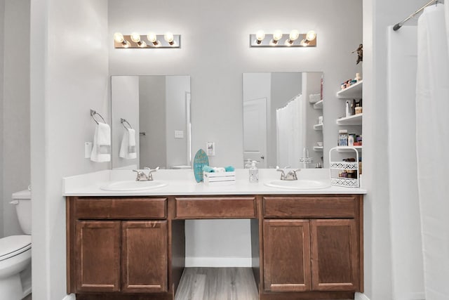 full bath featuring double vanity, a sink, wood finished floors, and toilet