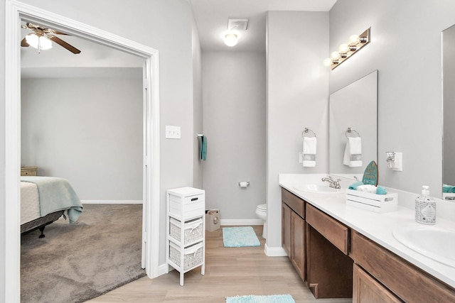ensuite bathroom featuring a ceiling fan, double vanity, toilet, ensuite bathroom, and a sink