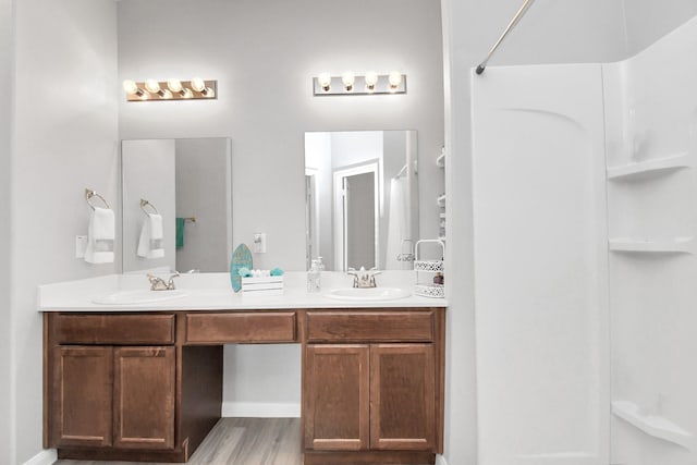 full bath featuring double vanity, a sink, and a shower