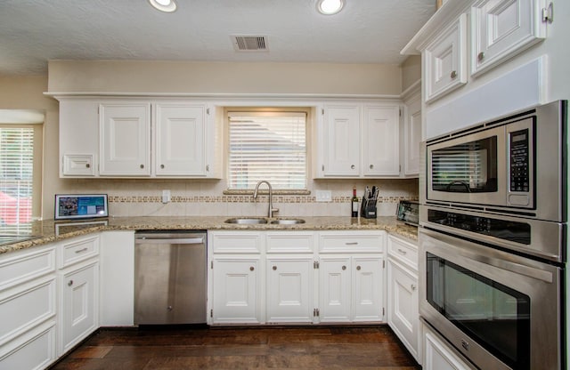 6711 Pebble Beach Dr, Houston, TX 77069 - kitchen featuring stainless steel appliances, a sink, white cabinetry, light stone counters, and dark wood finished floors