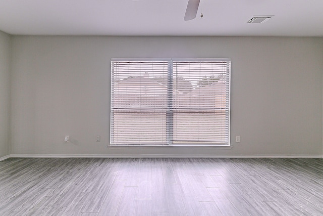 unfurnished room with visible vents, baseboards, ceiling fan, and wood finished floors