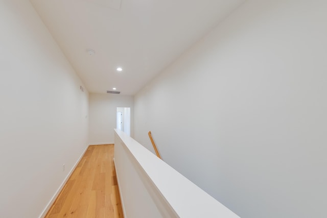 corridor featuring an upstairs landing, light wood-style floors, baseboards, visible vents, and recessed lighting