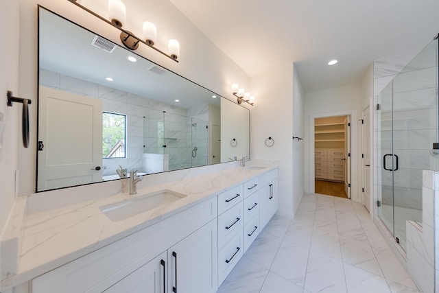 bathroom with a spacious closet, a sink, double vanity, and a stall shower